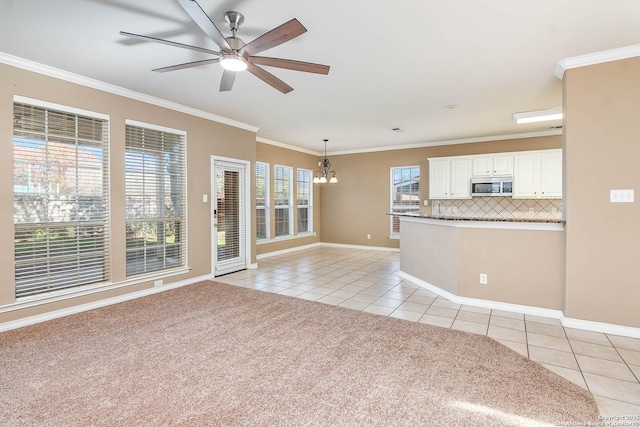 unfurnished living room with light tile patterned flooring, ornamental molding, and ceiling fan with notable chandelier