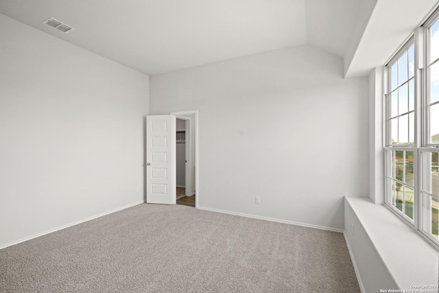 carpeted empty room featuring vaulted ceiling