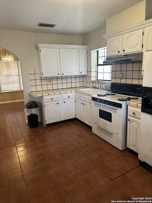 kitchen featuring white gas range, sink, and white cabinets