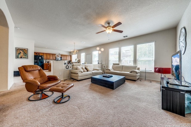 carpeted living room with ceiling fan with notable chandelier and a textured ceiling