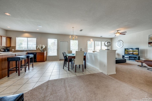 carpeted dining area featuring ceiling fan with notable chandelier and a textured ceiling