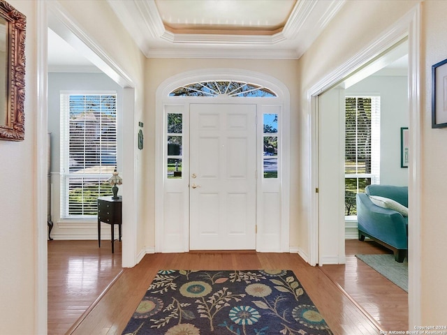 entryway with hardwood / wood-style flooring, crown molding, and a tray ceiling