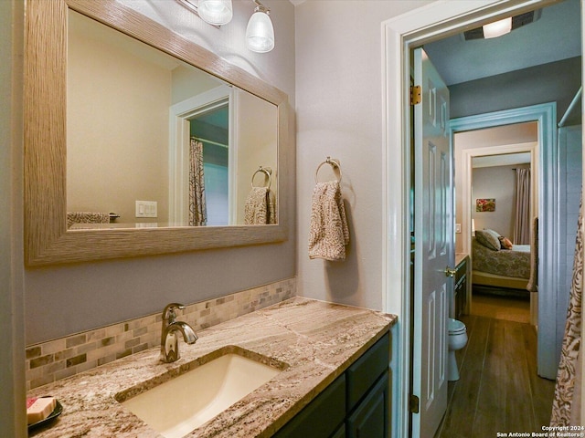 bathroom featuring tasteful backsplash, vanity, wood-type flooring, and toilet