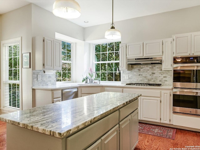 kitchen with pendant lighting, appliances with stainless steel finishes, a kitchen island, and white cabinets