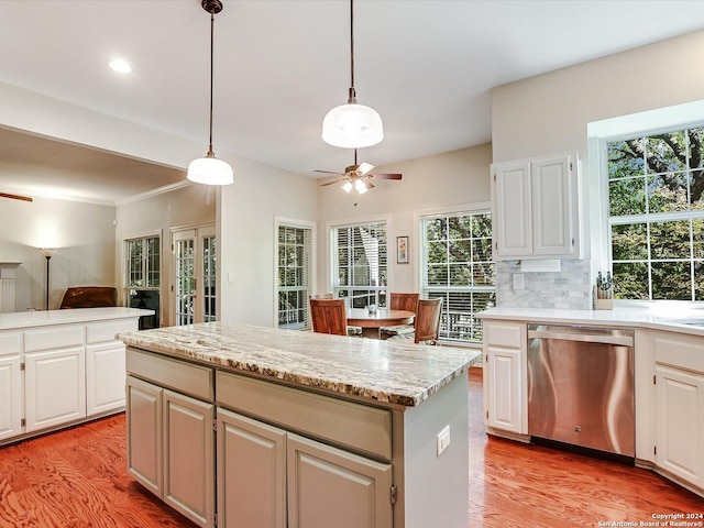 kitchen featuring white cabinetry, decorative light fixtures, stainless steel dishwasher, a kitchen island, and ceiling fan