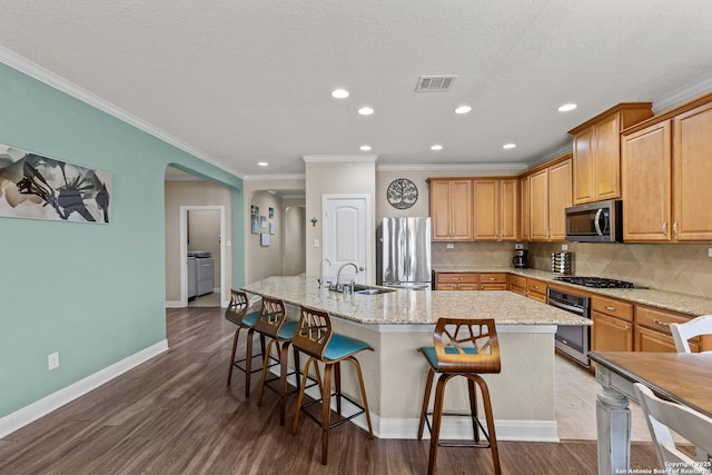 kitchen featuring a breakfast bar, sink, ornamental molding, an island with sink, and stainless steel appliances