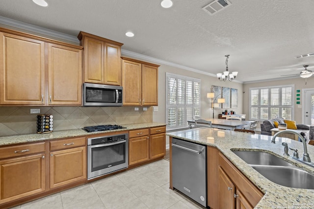 kitchen featuring sink, appliances with stainless steel finishes, ornamental molding, decorative backsplash, and decorative light fixtures