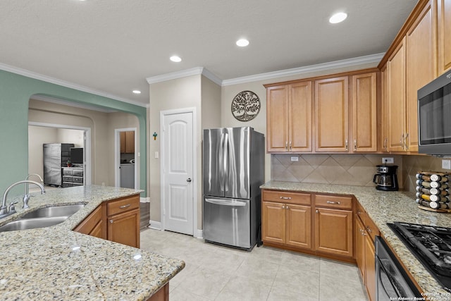 kitchen featuring sink, decorative backsplash, light stone countertops, and stainless steel refrigerator