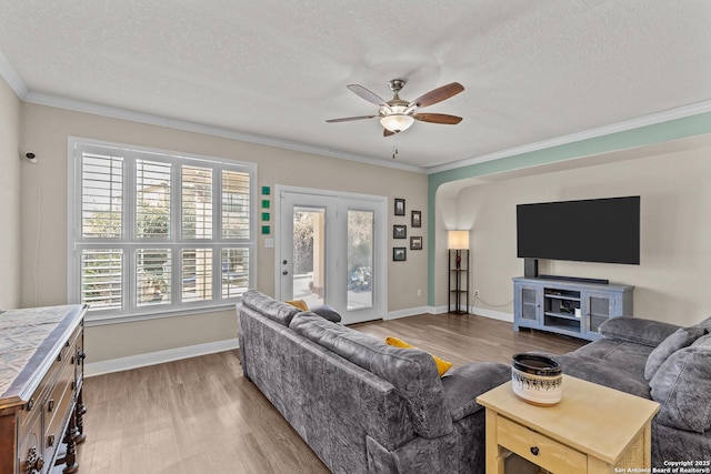 living room with crown molding, ceiling fan, light hardwood / wood-style floors, and a textured ceiling