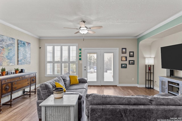 living room featuring crown molding, ceiling fan, a textured ceiling, and light wood-type flooring