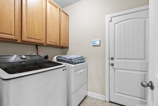 washroom featuring cabinets, washer and clothes dryer, and light tile patterned floors