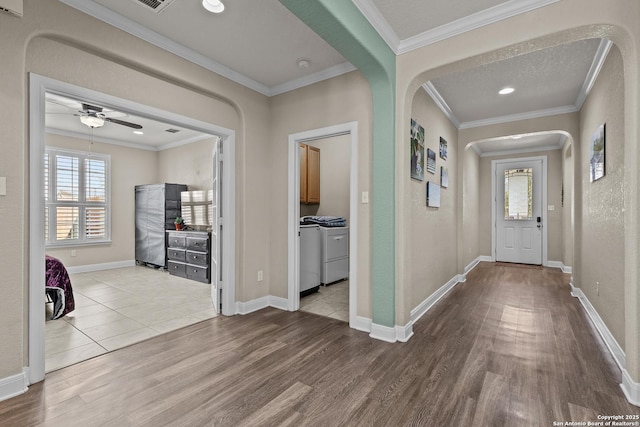 foyer with crown molding, ceiling fan, washing machine and dryer, and light wood-type flooring