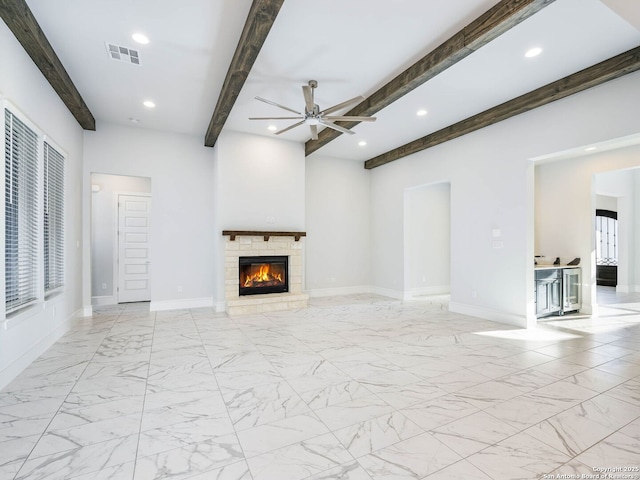 unfurnished living room featuring ceiling fan, a stone fireplace, and beamed ceiling