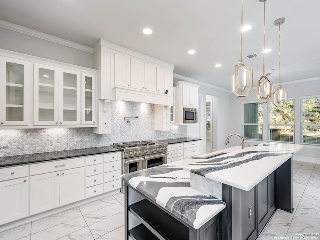 kitchen featuring sink, white cabinets, a large island with sink, hanging light fixtures, and stainless steel appliances