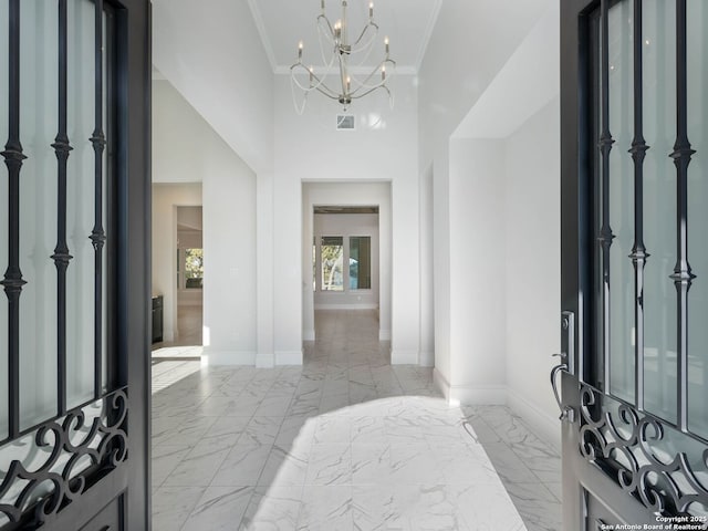 foyer entrance featuring ornamental molding, a towering ceiling, and a chandelier