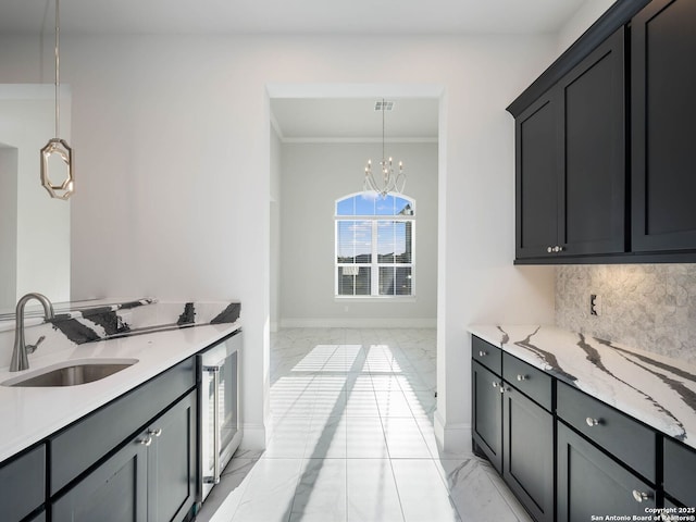 kitchen with pendant lighting, tasteful backsplash, sink, light stone counters, and an inviting chandelier