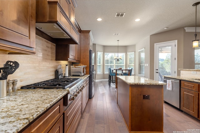 kitchen with light stone counters, a center island, appliances with stainless steel finishes, dark hardwood / wood-style floors, and pendant lighting