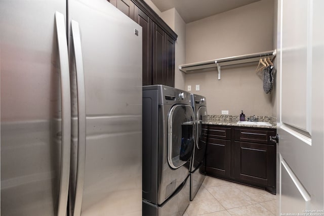 laundry room with cabinets, washing machine and clothes dryer, sink, and light tile patterned floors