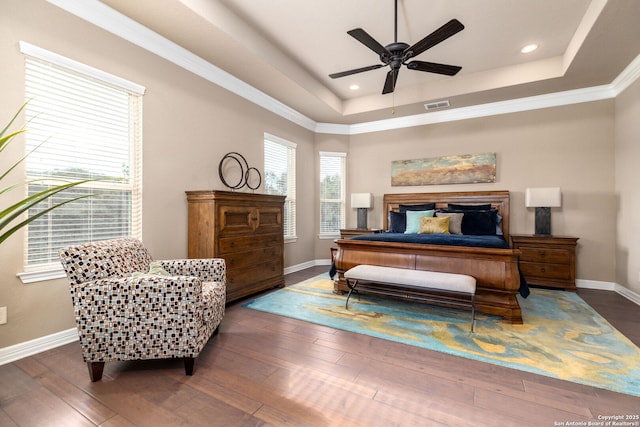 bedroom with a raised ceiling, crown molding, dark wood-type flooring, and ceiling fan