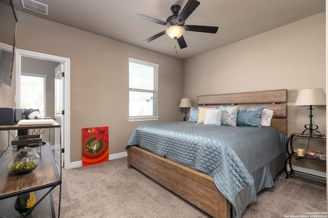 carpeted bedroom featuring multiple windows and ceiling fan