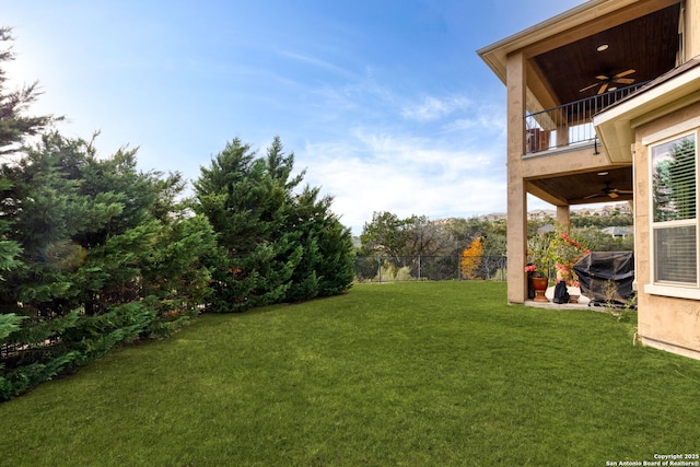 view of yard featuring a balcony and ceiling fan