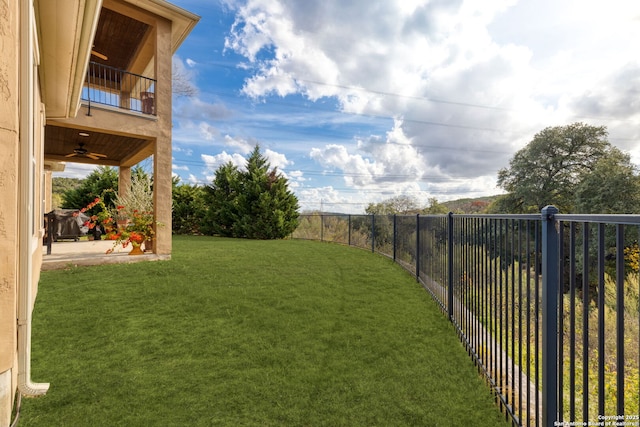 view of yard featuring ceiling fan and a balcony