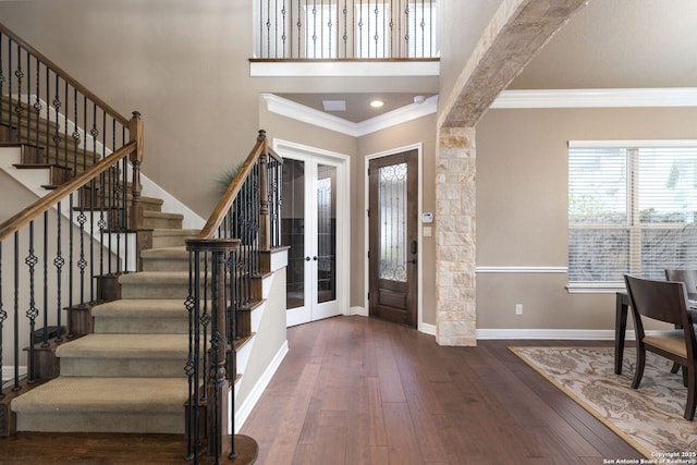 entrance foyer featuring french doors, crown molding, dark hardwood / wood-style flooring, and a high ceiling