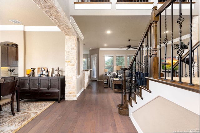 foyer entrance featuring dark wood-type flooring, ceiling fan, crown molding, and ornate columns