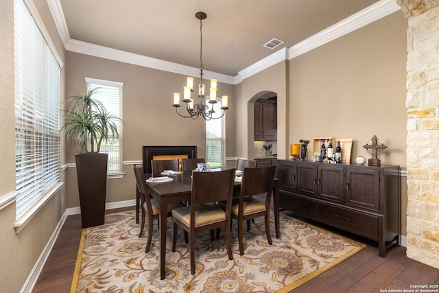 dining area with an inviting chandelier, dark wood-type flooring, and ornamental molding