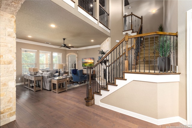 stairway featuring crown molding, wood-type flooring, a textured ceiling, and ceiling fan