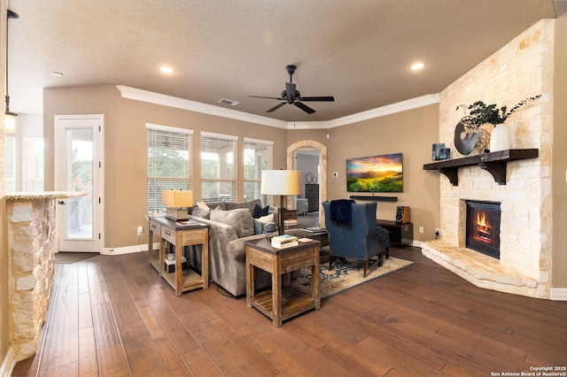 living room featuring hardwood / wood-style floors, crown molding, a fireplace, and a textured ceiling