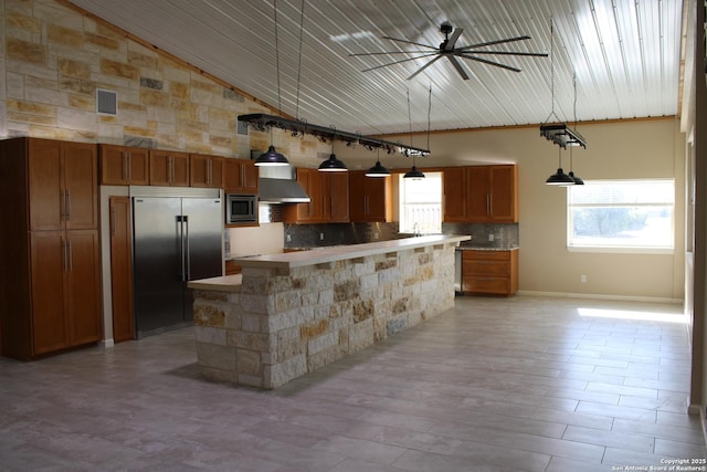 kitchen featuring tasteful backsplash, built in appliances, a center island, hanging light fixtures, and ceiling fan