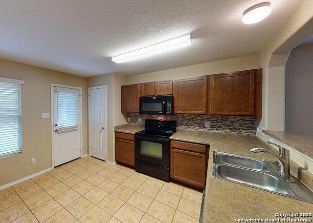 kitchen featuring light tile patterned flooring, tasteful backsplash, sink, black appliances, and a textured ceiling