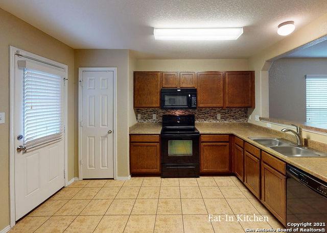 kitchen featuring sink, tasteful backsplash, black appliances, a textured ceiling, and light tile patterned flooring