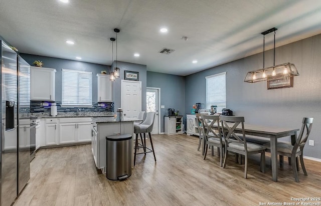 kitchen with light hardwood / wood-style flooring, decorative light fixtures, a kitchen island, and white cabinets