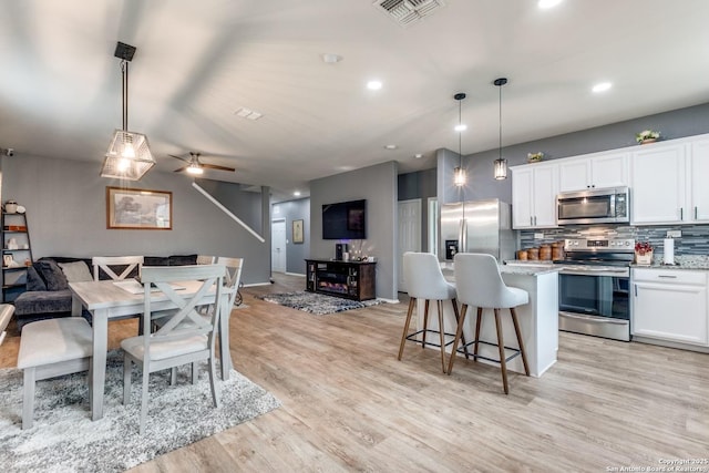 kitchen with a breakfast bar, pendant lighting, white cabinetry, a center island, and stainless steel appliances