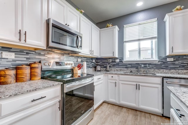 kitchen featuring light stone counters, appliances with stainless steel finishes, sink, and white cabinets