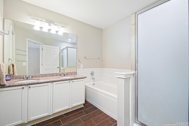 bathroom featuring a stall shower, wood tiled floor, a sink, and double vanity