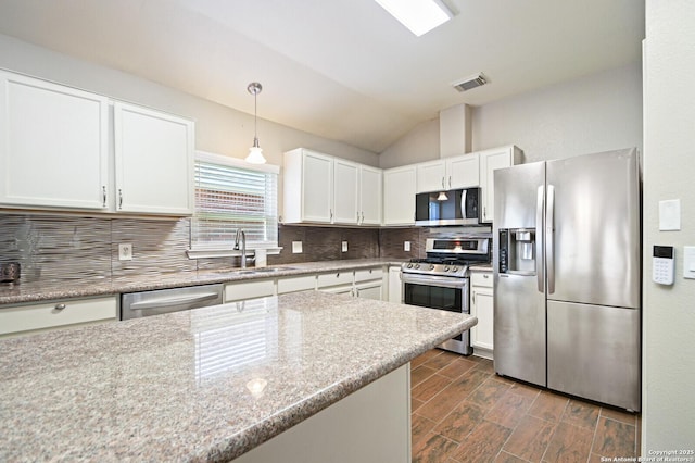 kitchen with stainless steel appliances, wood finish floors, a sink, visible vents, and decorative backsplash