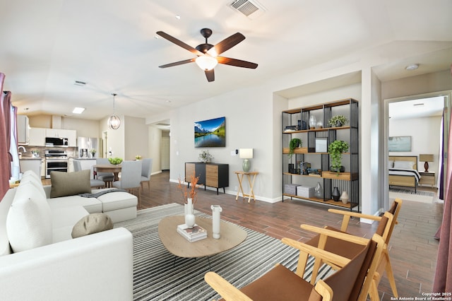 living area featuring lofted ceiling, baseboards, visible vents, and wood finished floors