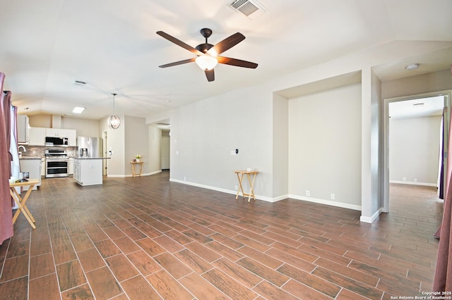 unfurnished living room with dark wood-style flooring, visible vents, vaulted ceiling, and ceiling fan