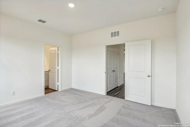 unfurnished bedroom with connected bathroom and dark carpet