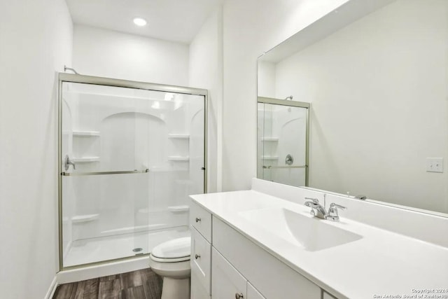 bathroom with walk in shower, vanity, toilet, and hardwood / wood-style floors