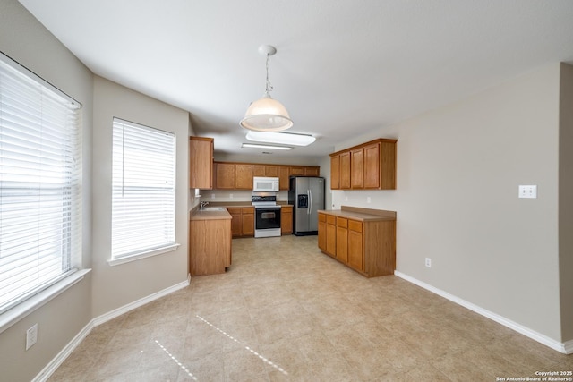 kitchen featuring stainless steel fridge, decorative light fixtures, sink, and electric range