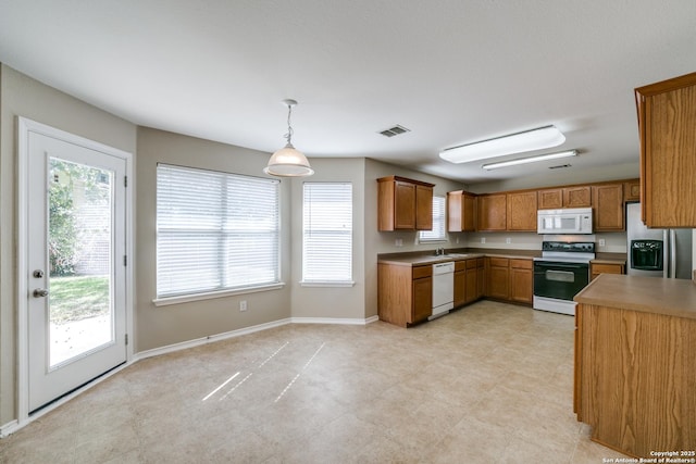 kitchen with sink, white appliances, and decorative light fixtures