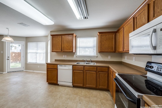 kitchen with white appliances, plenty of natural light, decorative light fixtures, and sink