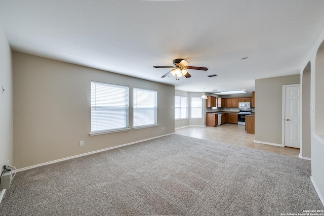 unfurnished living room with light carpet and ceiling fan