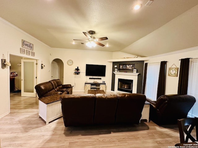 living room featuring ceiling fan, ornamental molding, a textured ceiling, vaulted ceiling, and light wood-type flooring