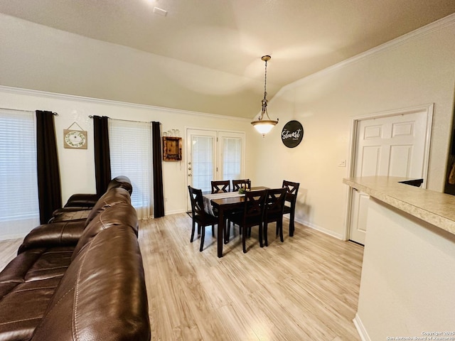 dining room featuring light hardwood / wood-style flooring, ornamental molding, french doors, and vaulted ceiling