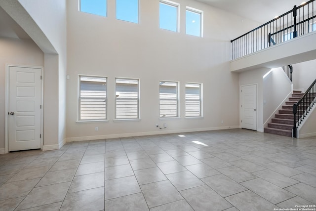 unfurnished living room with a towering ceiling and light tile patterned floors